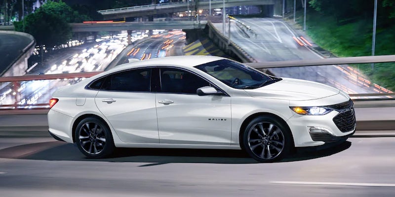 White Chevrolet Malibu sedan driving on a city roadway at night