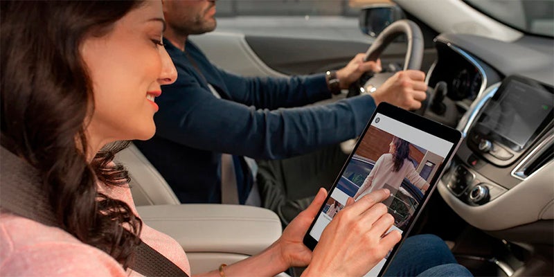 Vehicle passenger using a tablet inside the Chevrolet Malibu while seated in the front passenger seat
