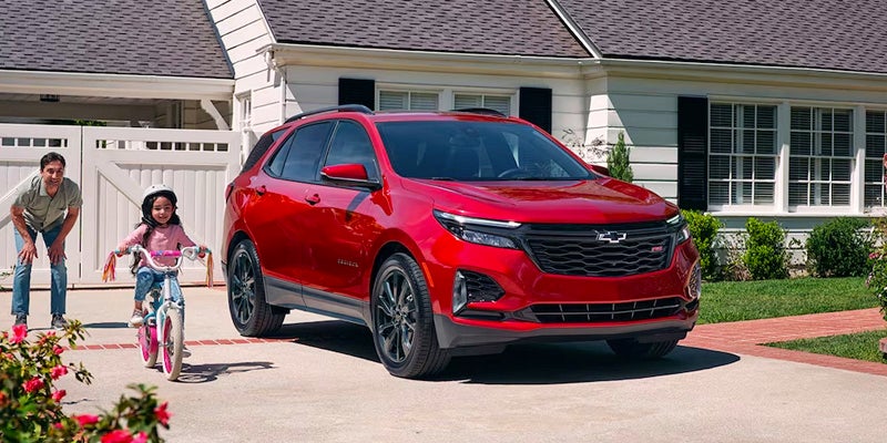 Red Chevrolet Equinox SUV parked in a suburban driveway in front of a house