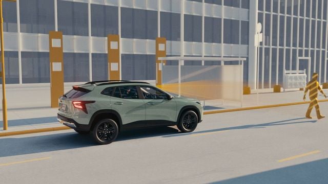 Light green Chevrolet SUV driving on a city street past modern office buildings